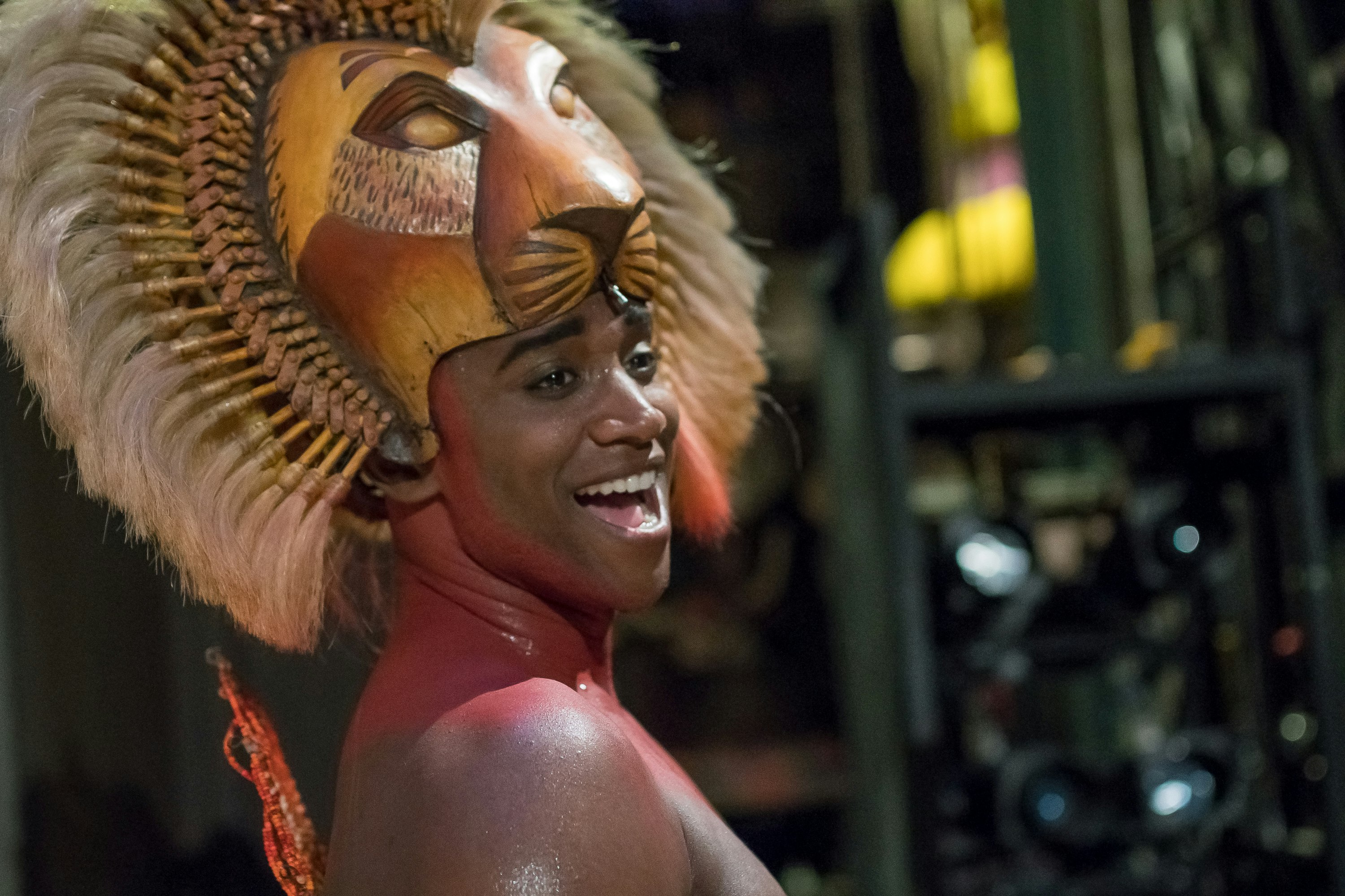 An actor smiles, wearing a lion headdress